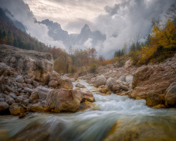 Raging river with rocky banks and misty mountains in the background