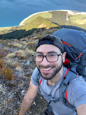 Jamil Slim with a backpack taking a selfie in a mountainous landscape