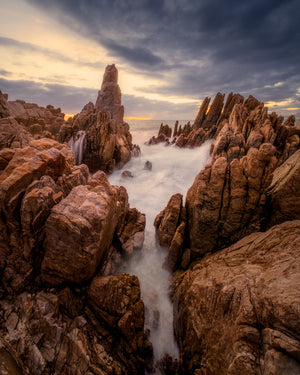 Rugged coastal landscape with rocky outcrops and a flowing stream.